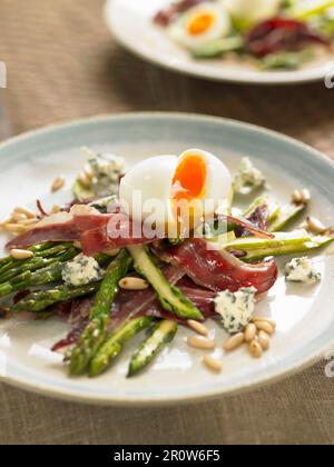 Fried wild asparagus and duck ham, soft-boiled egg and pine nuts Stock Photo