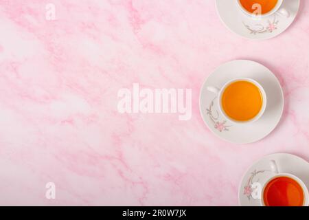 Three cups of tea on pink background. Top view. Copy space. Stock Photo