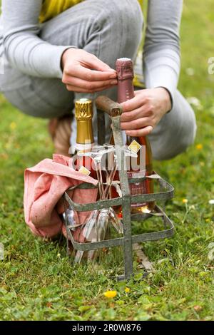 Person openning a bottle of Champagne in a metal bottle carrier Stock Photo