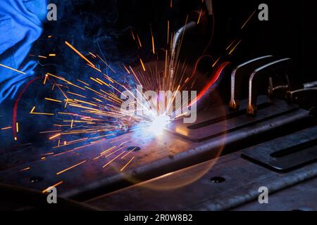Worker in heavy industry wearing protective clothing wearing on argon welding mask to weld steel an factorie Stock Photo