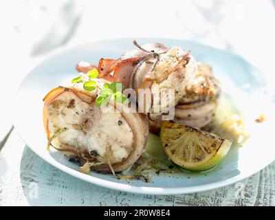 Monkfish wrapped in bacon with lemon Stock Photo