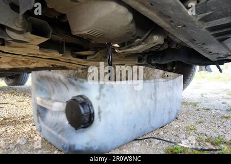 Black used oil drained from the car's engine. Draining old car oil. Oil changing in the car. Car oil change. Stock Photo