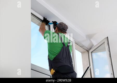 Worker in uniform installing window indoors, back view Stock Photo