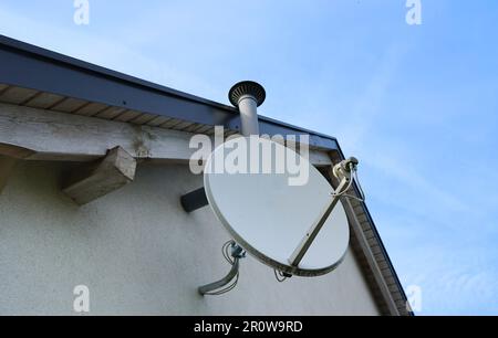 Satellite dish on the roof. Dish aerial installed to the wall. Receiving tv signals. Tv and internet connection aerial. Stock Photo