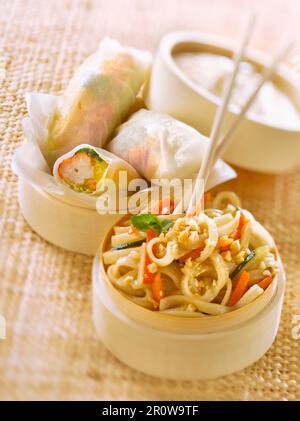 Spring rolls with crab meat and fried noodles with carrot, courgette and peanuts Stock Photo