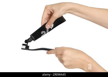 Woman applying charcoal toothpaste on brush against white background, closeup Stock Photo