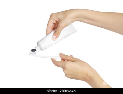 Woman applying charcoal toothpaste on brush against white background, closeup Stock Photo
