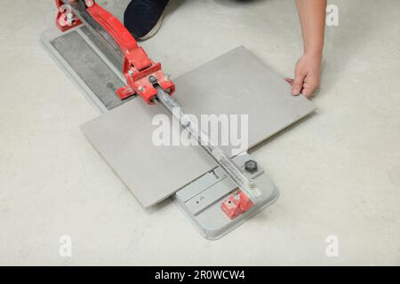 Worker using manual tile cutter on floor, closeup Stock Photo