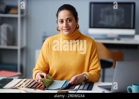 Portrait of young designer looking at camera while working with palette at her workplace in office Stock Photo