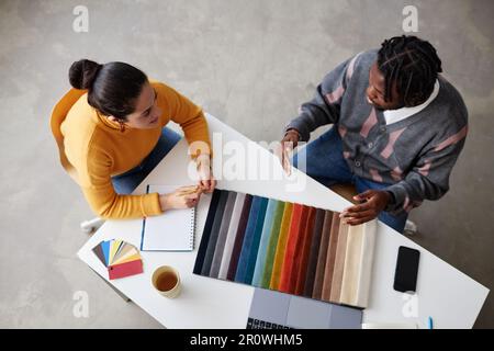 High angle view of designers using colorful palette and discussing color for future interior while sitting at table at meeting Stock Photo