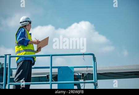 Solar engineers visually examine panel arrays on farm sites using blueprints and drawings to ensure that the alignment, surface, sunlight access, and Stock Photo