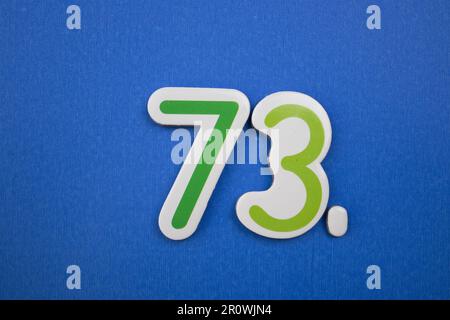The number 73 in green, photographed from above, placed on the edge of ...