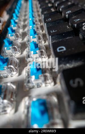 A dirty computer keyboard which has had two rows of key facias removed for cleaning revealing microswitches below Stock Photo