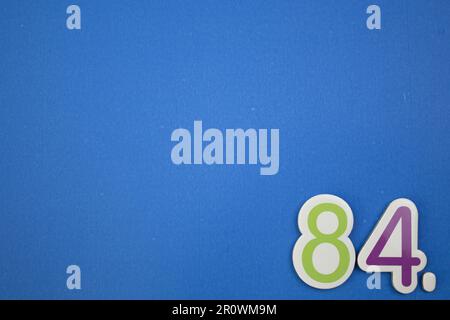 The number 84, placed on a blue background, photographed from above ...