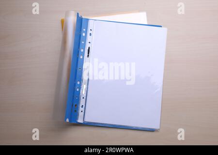 File folder with punched pockets and paper sheets on wooden table, top view Stock Photo