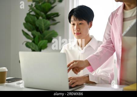 Focused young Asian male office worker is being trained and working with his senior manager in the office. Stock Photo