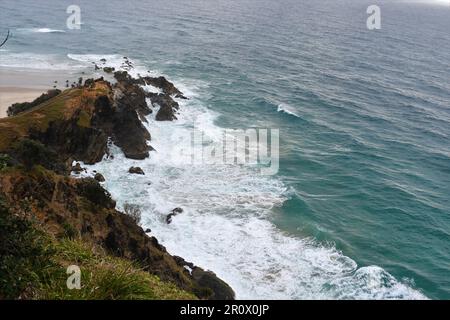 Aerial top view of ocean's beautiful waves crashing on the rocky cliff of Byron bay coast taken from lighthouse area Stock Photo