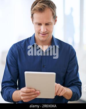 Getting those emails out of the way. a handsome man using his tablet at home. Stock Photo