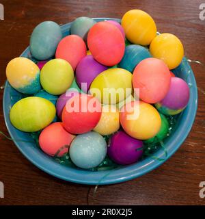 A close-up of a bowl of colorful bowl of Easter eggs on a wooden table Stock Photo