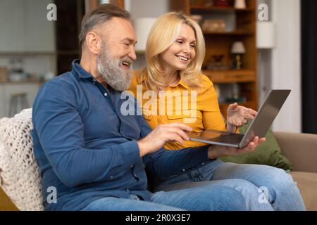 Side View Of Happy Mature Couple Using Laptop At Home Stock Photo