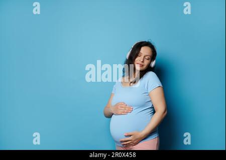 Attractive pregnant woman gently stroking her big belly, experiencing  wonderful emotions feeling baby moves. Pregnancy 27029634 Stock Photo at  Vecteezy