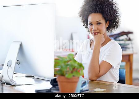 Young and focused on her career. Portrait of a focused young designer working on a computer at a desk in an office. Stock Photo