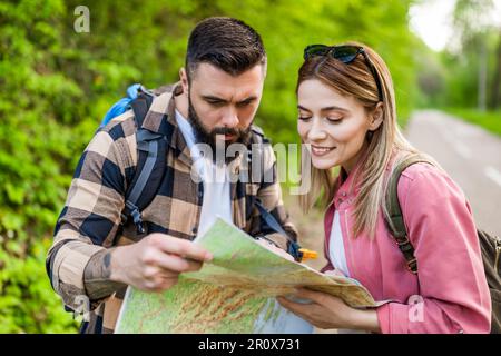 Happy couple hiking in nature and looking at map. Couple enjoying their vacation. Stock Photo