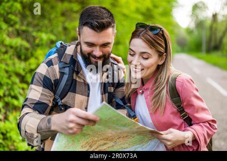 Happy couple hiking in nature and looking at map. Couple enjoying their vacation. Stock Photo