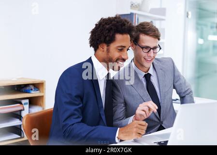 Theyre working on the solution. male colleagues working together on a laptop. Stock Photo