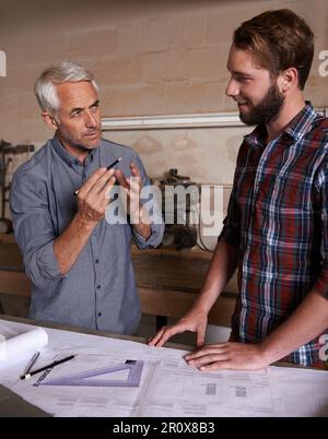 Architecture team, working on blueprint in workshop, designer and engineering collaboration. Senior mentor, male training architect and work together Stock Photo