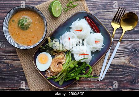 Kanom Jeen Nam Prik - Thai rice noodles with peanut sauce at top view on wood table Stock Photo