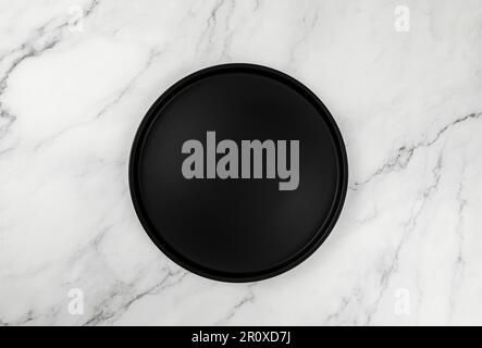 Top view of black plate on white marble background. Food presentation flat lay. Copy space. Stock Photo