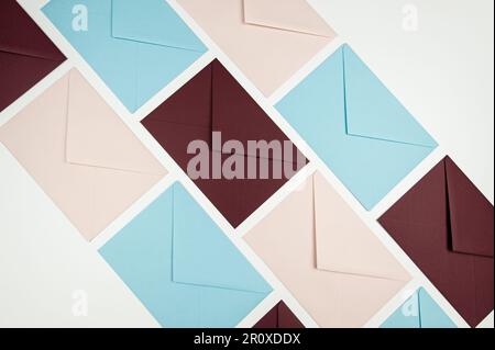 Top view of colourful envelopes on white background. Pink, blue and dark red envelopes flat lay. Post, copy space. Stock Photo