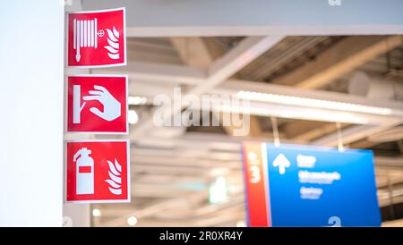 A red emergency fire exit direction plate that installed on the white door at the department store. Safety sign for transportation mode. Stock Photo