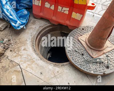 The manhole cover was opened for maintenance time near the sidewalk in the  city , front view with the copy space. Stock Photo