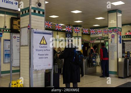 A diverse group of people with suitcases waiting in a busy train station Stock Photo