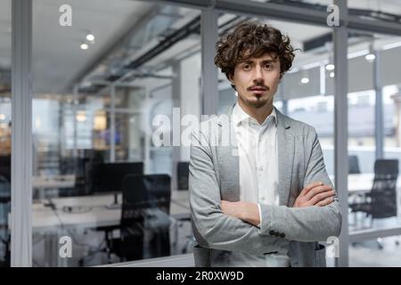 Portrait of hispanic businessman inside modern office, boss serious looking at camera, man with crossed arms thinking worker. Stock Photo