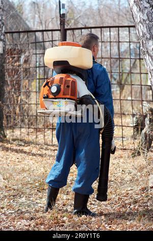 man in protective suit in the open air treats grass in the country from mosquitoes and ticks in the spring. Destruction of dangerous insects Stock Photo