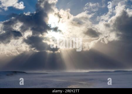Panoramic high level view over snow covered landscape with river and mountains in Iceland with dramatic cloudscape of dark snowclouds Stock Photo