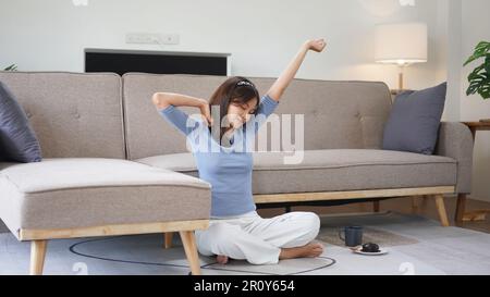 Work from home concept, Business women sit on floor and stretching to relax after working at home. Stock Photo