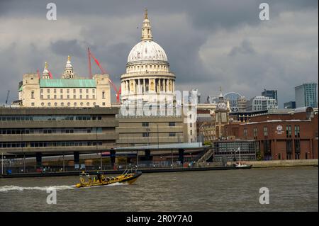 LONDON - April 21, 2023: Iconic St Paul's Cathedral captured from across the River Thames on a grey day with a tour boat passing by Stock Photo