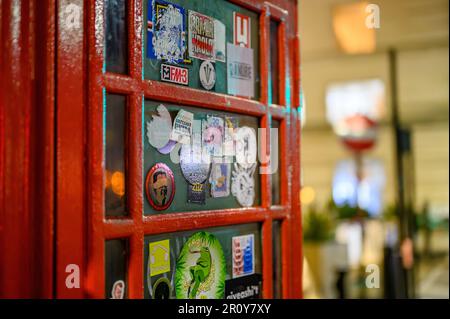 LONDON - April 21, 2023: Experience the vintage charm of London's traditional phone box covered in a plethora of unique stickers, captured in a stunni Stock Photo
