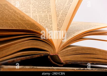 vintage old open book with some visible pages lying on top of other books with white background Stock Photo