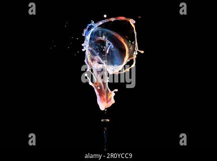 Falling drops of colored liquid, water splashes on a black background, motion blur Stock Photo