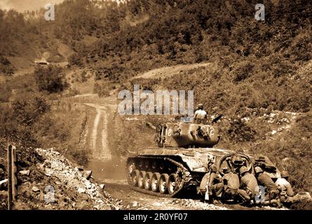 Marine infantrymen take cover behind a tank while it fires on Communist troops ahead.  Hongchon Area, May 22, 1951.  Photo by Sgt. John Babyak, Jr. (Marine Corps) Stock Photo