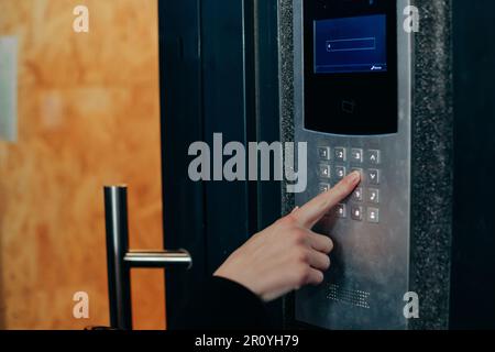 Woman hand press buttons on video intercom at entrance of apartment building in the night Stock Photo