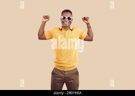 Young African American man smiles and demonstrates strength with muscular arms stands in studio Stock Photo