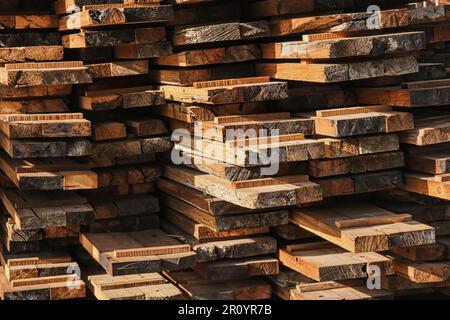 Wooden planks heap as background. Air-drying timber stack. Wood outdoors warehouse. Pile of wooden boards in sawmill, planking,  sawing boards. Stock Photo