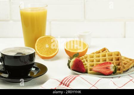 Belgian waffles and fresh fruit for breakfast. Fresh orange juice and coffee with Viennese waffles, Fresh flowers Stock Photo