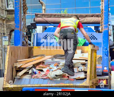 worker loading  skip on back of lorry Stock Photo